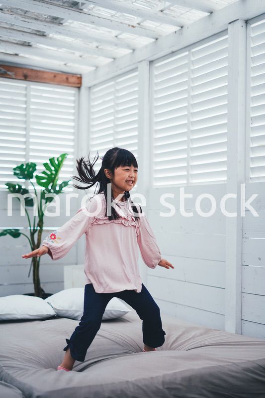 ベッドでジャンプをする小さな女の子