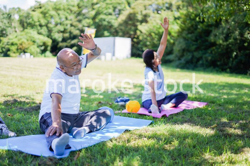 野外でヨガをする高齢者