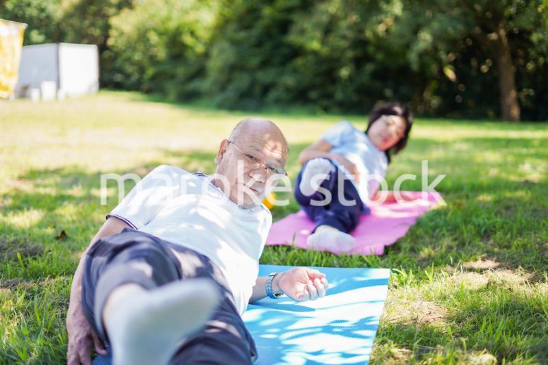 野外でヨガをする高齢者