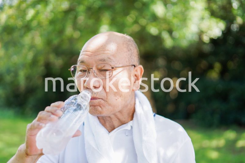 野外で水分補給をする高齢の男性