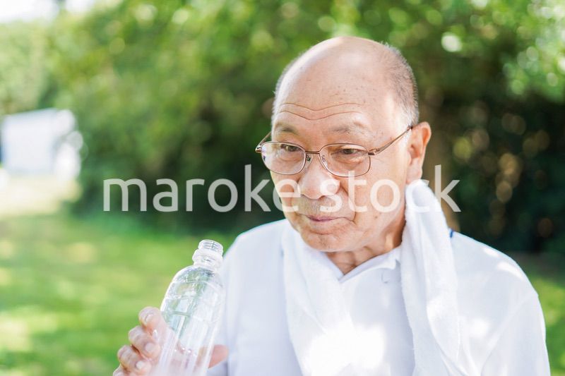 野外で水分補給をする高齢の男性
