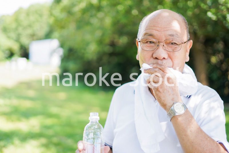 野外で水分補給をする高齢の男性