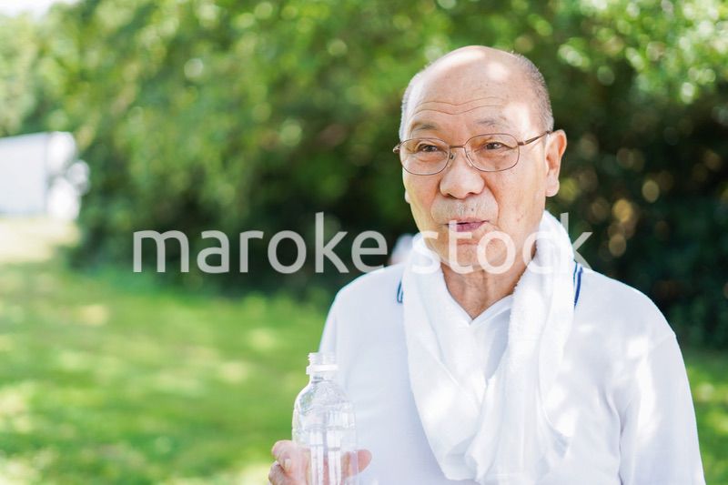 野外で水分補給をする高齢の男性