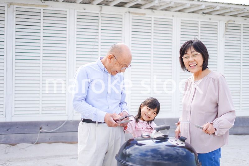 孫とバーベキューをする高齢の夫婦