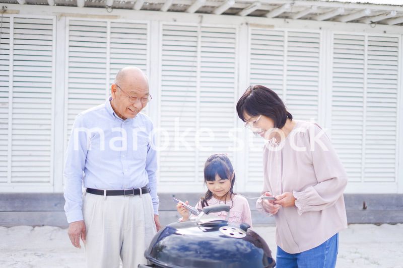 孫とバーベキューをする高齢の夫婦