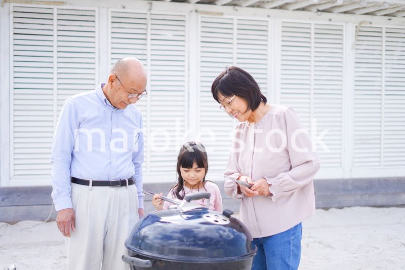 孫とバーベキューをする高齢の夫婦