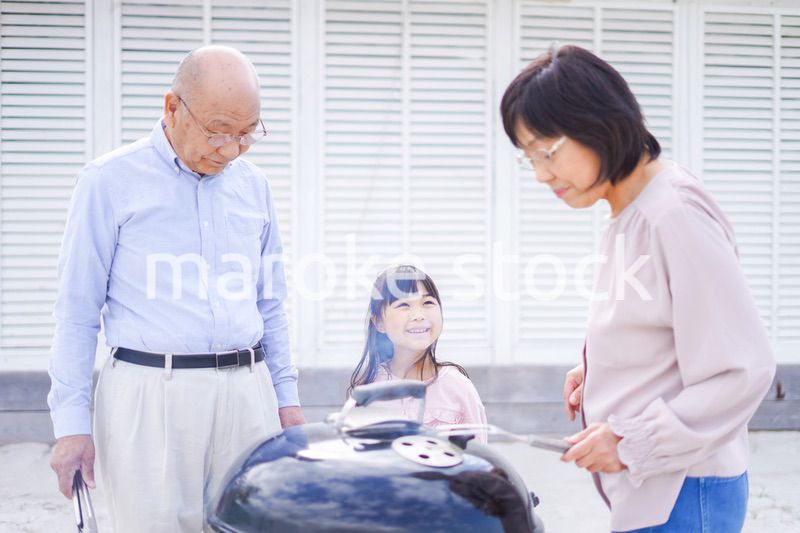 孫とバーベキューをする高齢の夫婦
