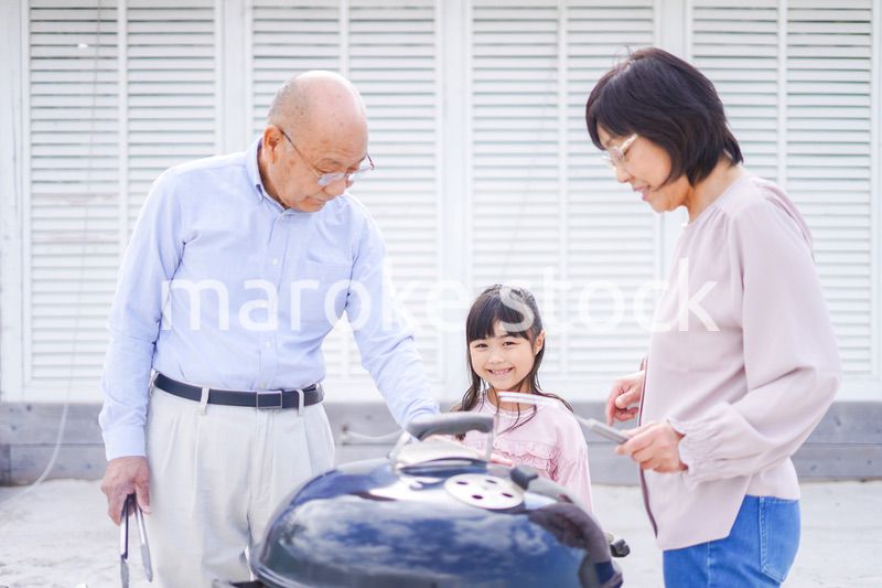 孫とバーベキューをする高齢の夫婦