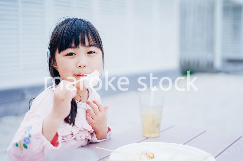 外でご飯を食べる小さな女の子