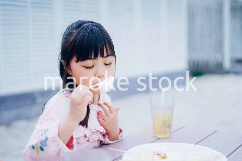 外でご飯を食べる小さな女の子