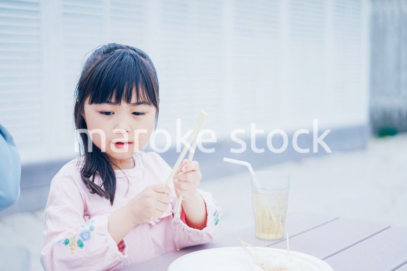 外でご飯を食べる小さな女の子