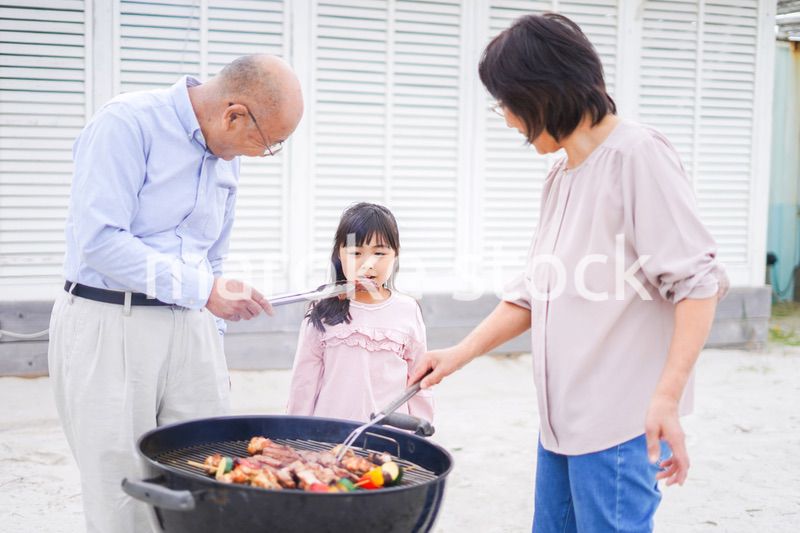 孫とバーベキューをする高齢の夫婦
