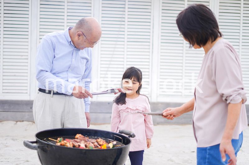 孫とバーベキューをする高齢の夫婦