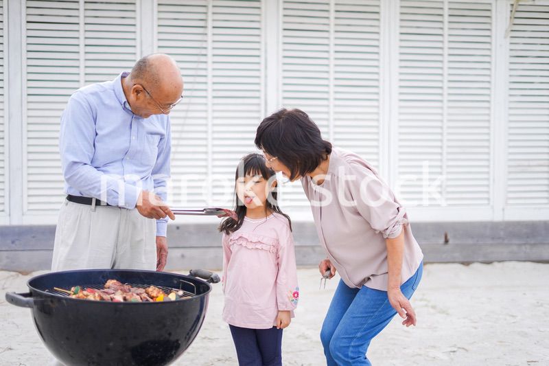 孫とバーベキューをする高齢の夫婦