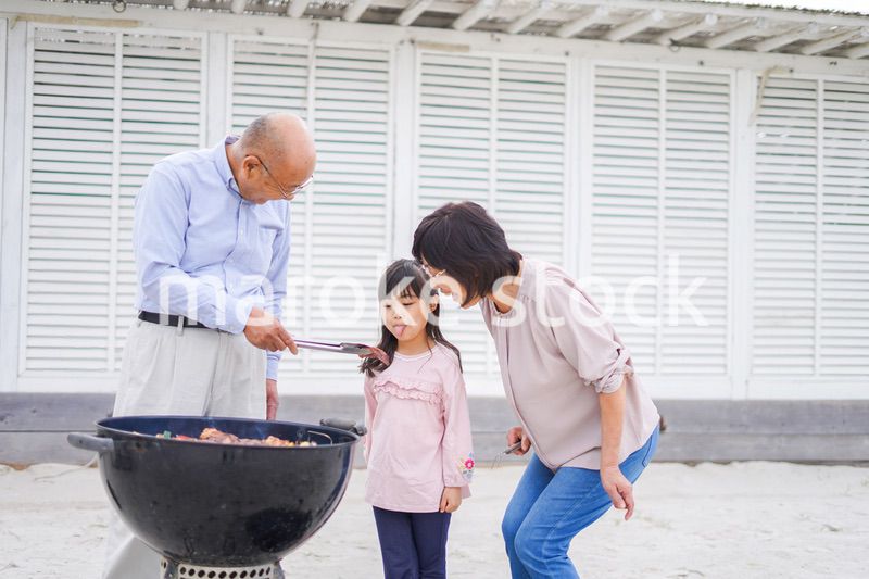 孫とバーベキューをする高齢の夫婦