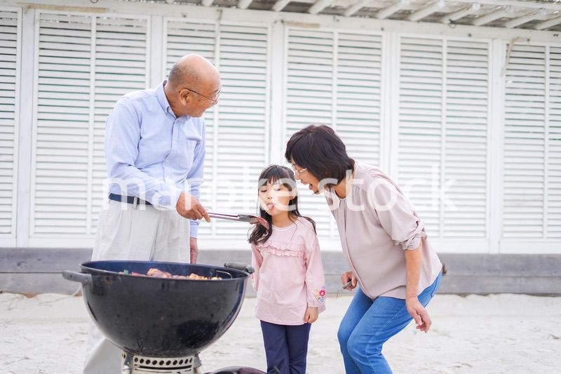 孫とバーベキューをする高齢の夫婦