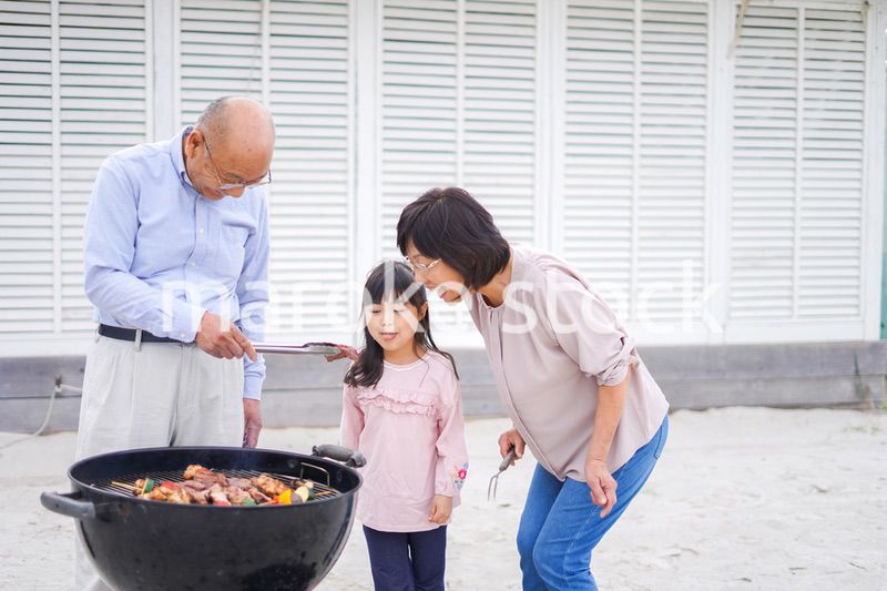 孫とバーベキューをする高齢の夫婦