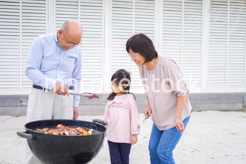 孫とバーベキューをする高齢の夫婦