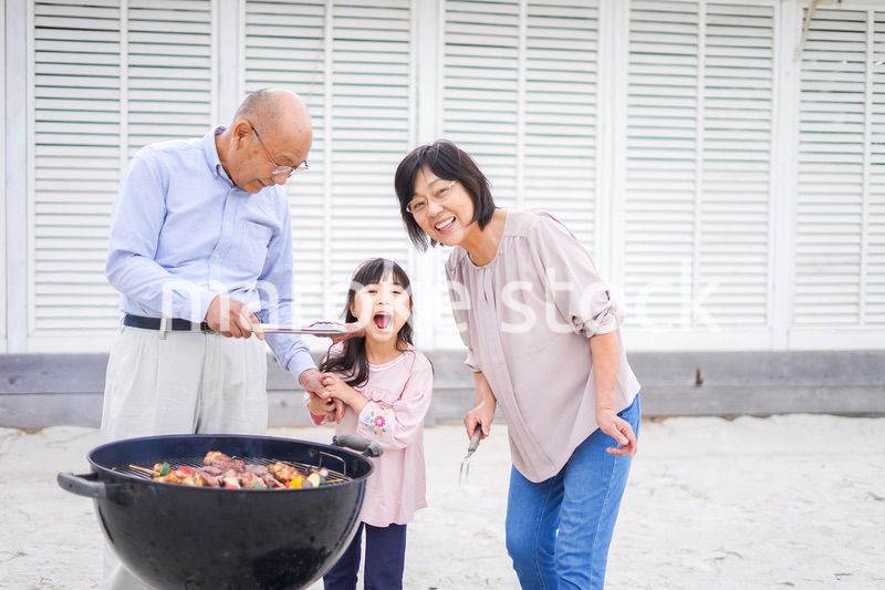 孫とバーベキューをする高齢の夫婦