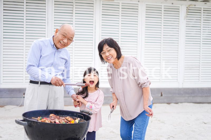 孫とバーベキューをする高齢の夫婦