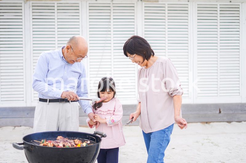孫とバーベキューをする高齢の夫婦