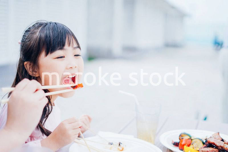 外でご飯を食べる小さな女の子