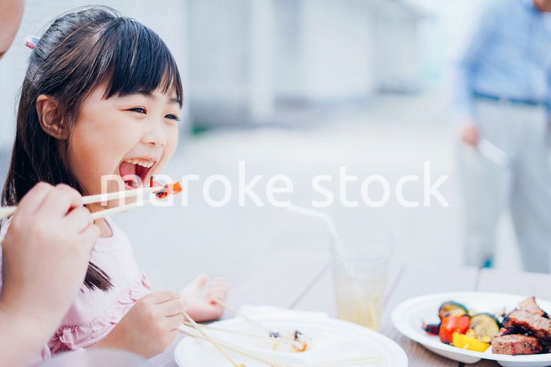 外でご飯を食べる小さな女の子