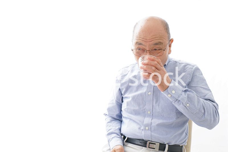 薬を飲む高齢男性