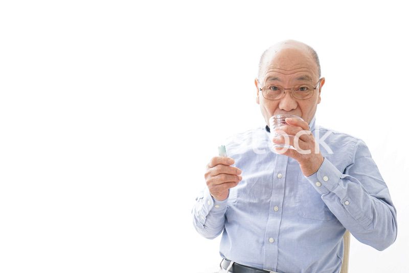 薬を飲む高齢男性