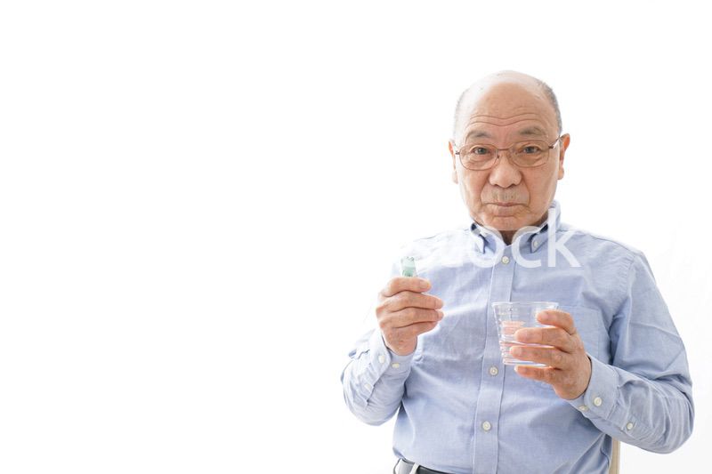薬を飲む高齢男性