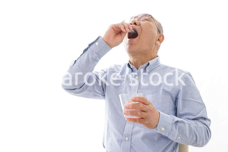 薬を飲む高齢男性