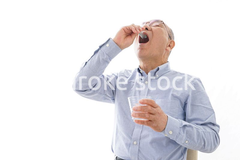 薬を飲む高齢男性