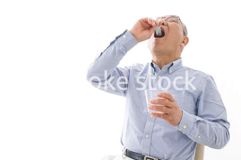 薬を飲む高齢男性
