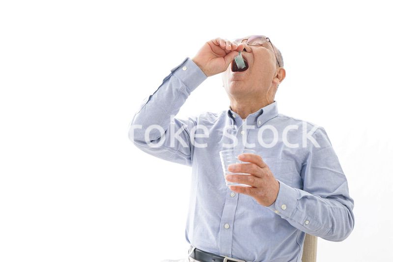 薬を飲む高齢男性