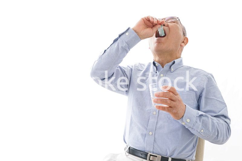 薬を飲む高齢男性
