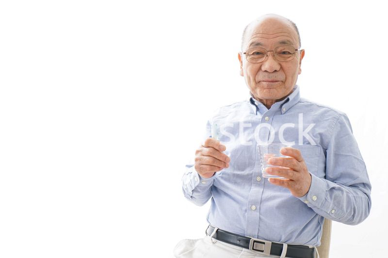 薬を飲む高齢男性