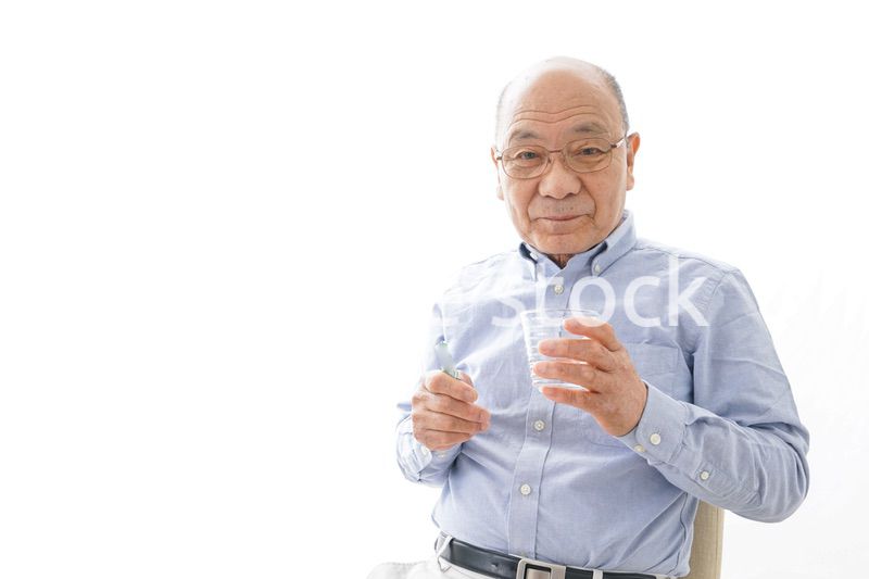 薬を飲む高齢男性