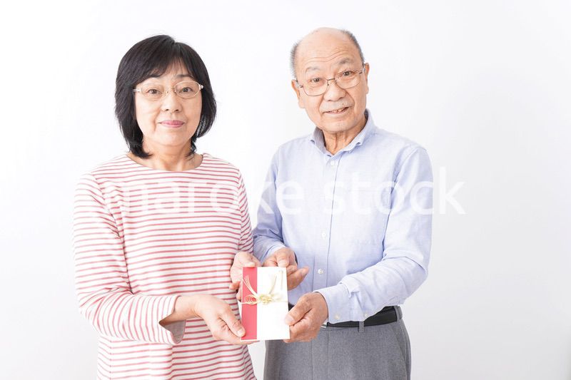 お祝いを渡すシニアの夫婦