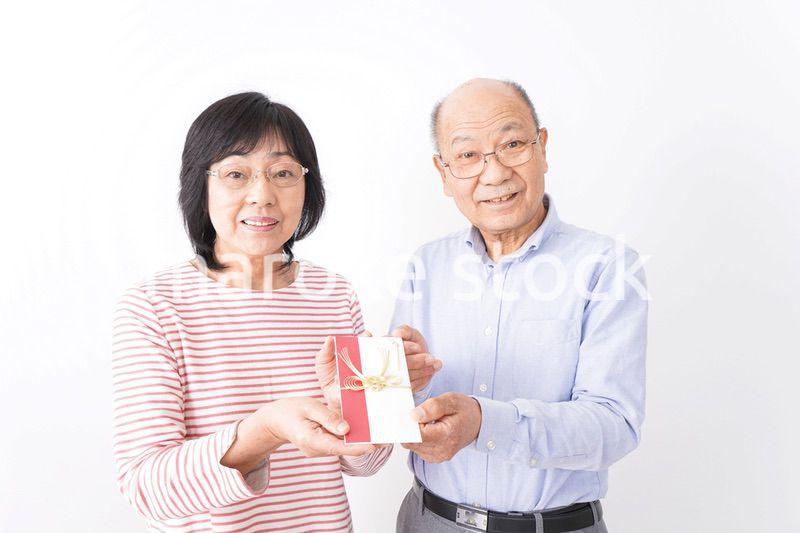 お祝いを渡すシニアの夫婦