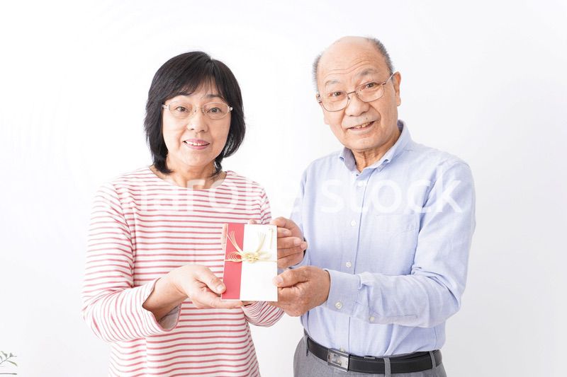 お祝いを渡すシニアの夫婦