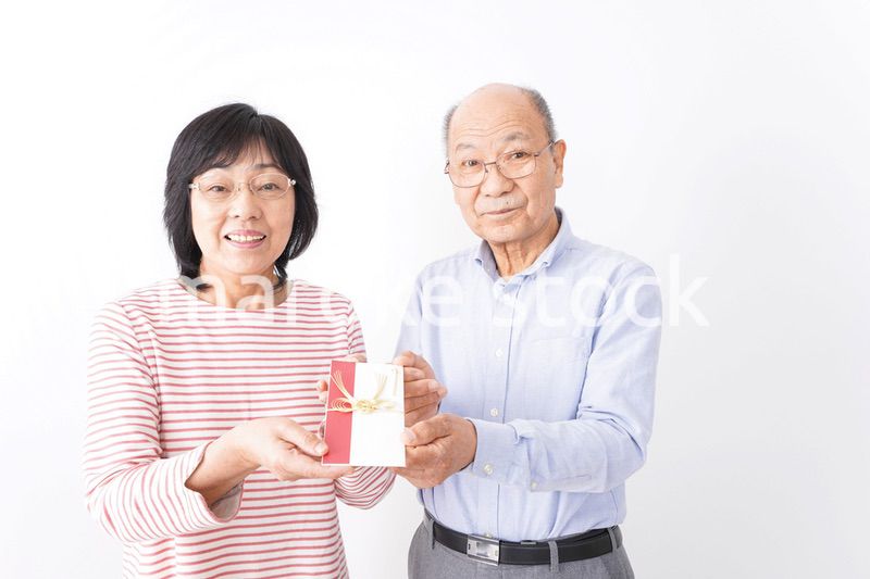 お祝いを渡すシニアの夫婦