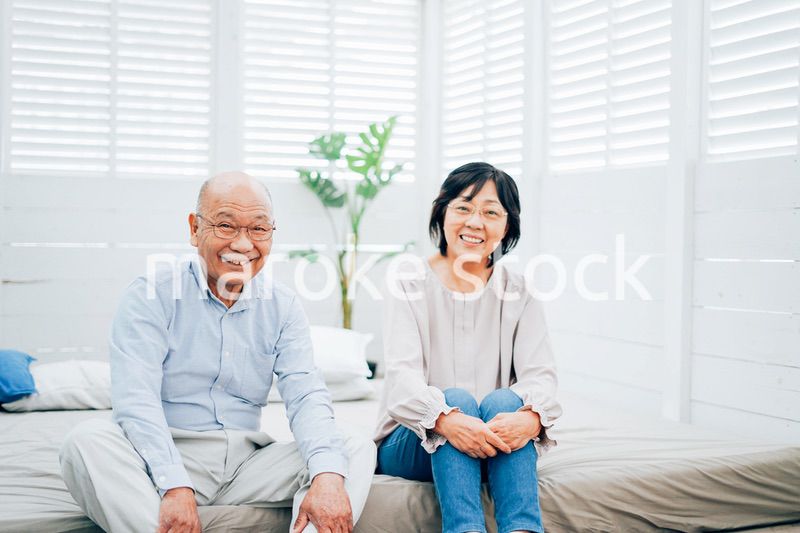 ベッドルームでくつろぐ高齢の夫婦