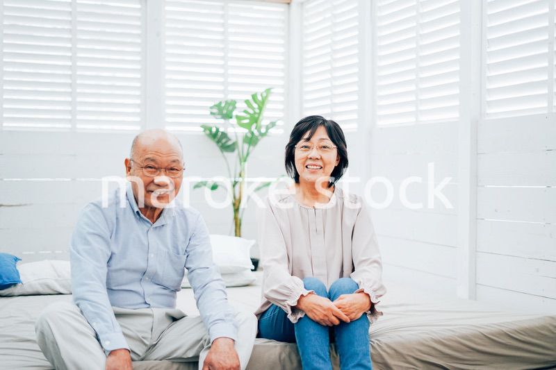 ベッドルームでくつろぐ高齢の夫婦