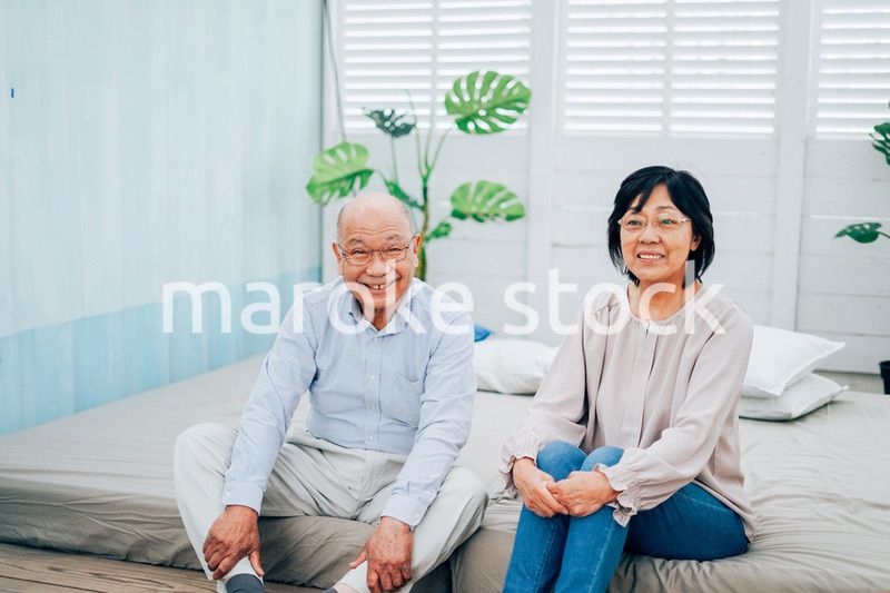 ベッドルームでくつろぐ高齢の夫婦