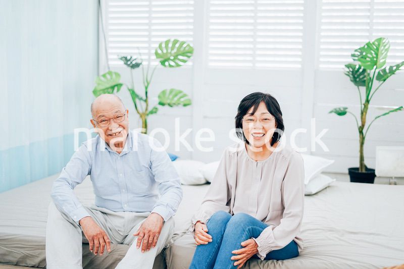 ベッドルームでくつろぐ高齢の夫婦