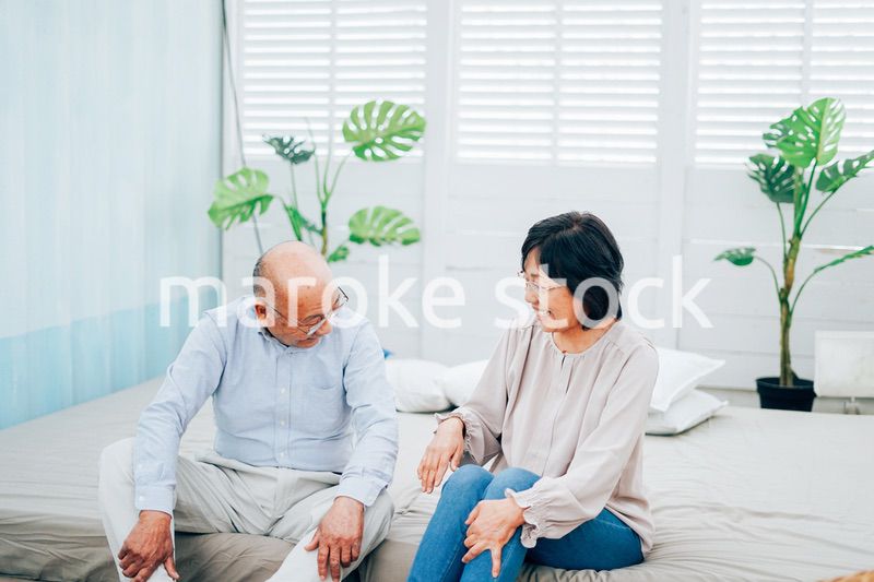 ベッドルームでくつろぐ高齢の夫婦