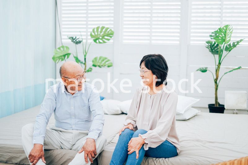 ベッドルームでくつろぐ高齢の夫婦