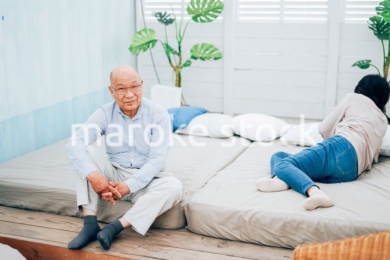 ベッドルームでくつろぐ高齢の夫婦