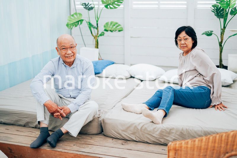 ベッドルームでくつろぐ高齢の夫婦