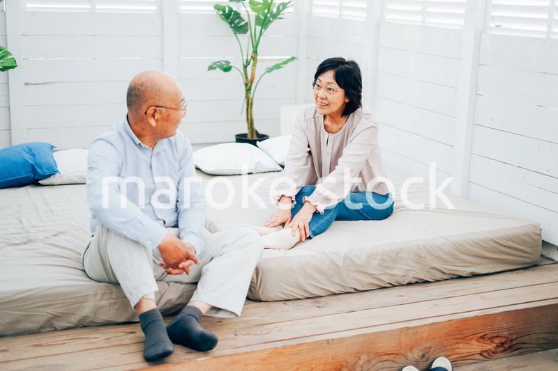 ベッドルームでくつろぐ高齢の夫婦